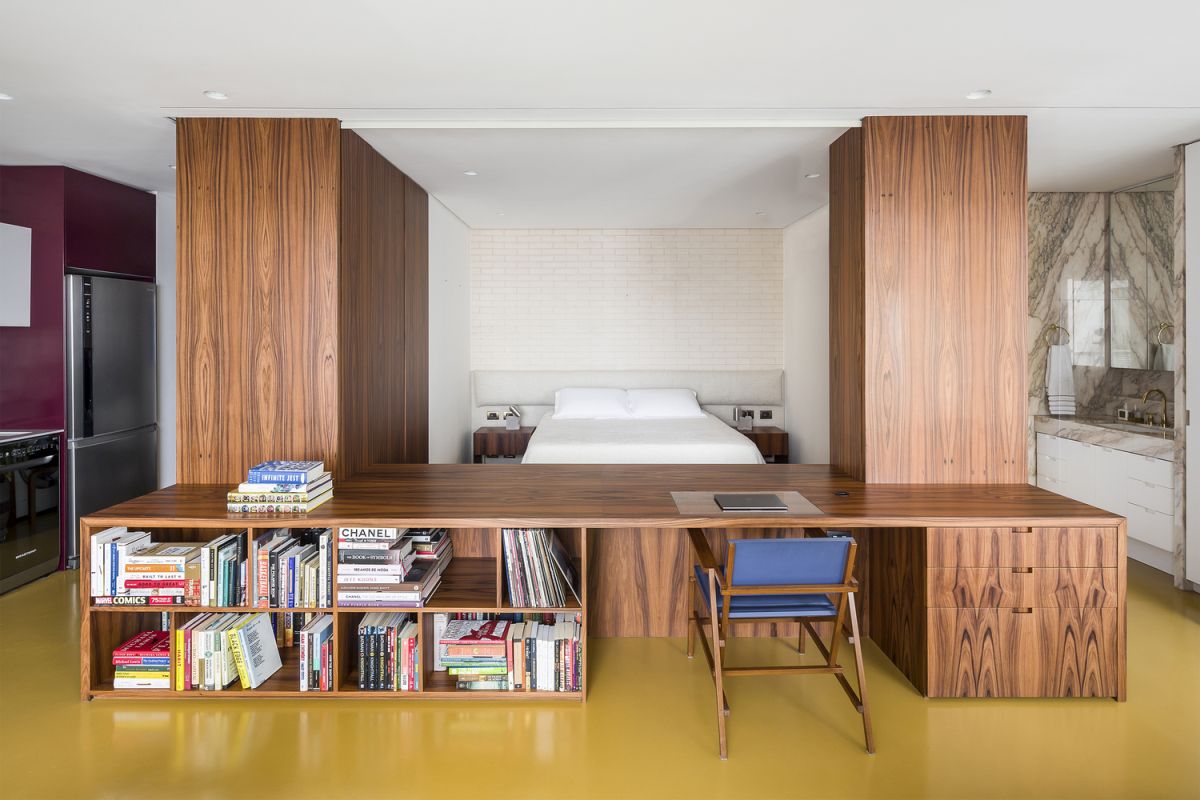 The bedroom is delineated by custom-built furniture units including two cabinets and a desk
